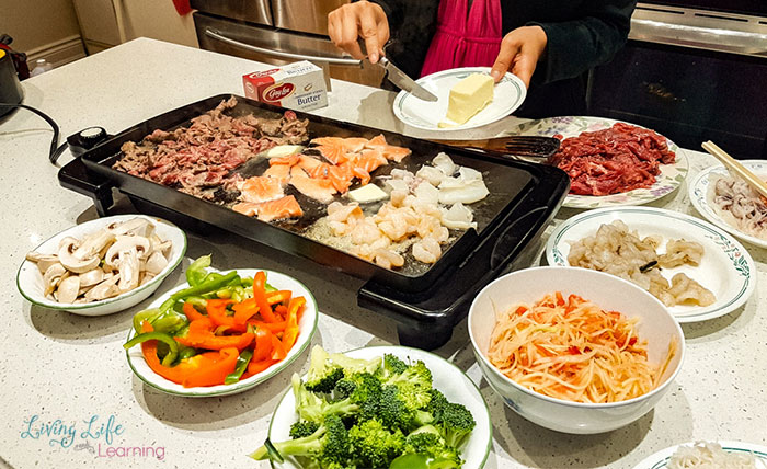 Table setting with all of the ingredients for Vietnamese butter beef and meat on the grill