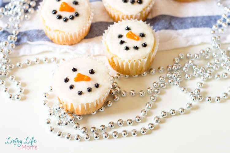 Four Simple Snowman Cupcakes on a table with a white and blue dish towel