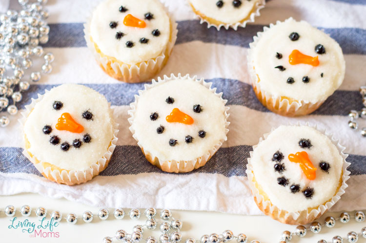 Snowman Cupcakes with frosted with white icing, black icing dots for eyes and a mouth and an orange icing nose.