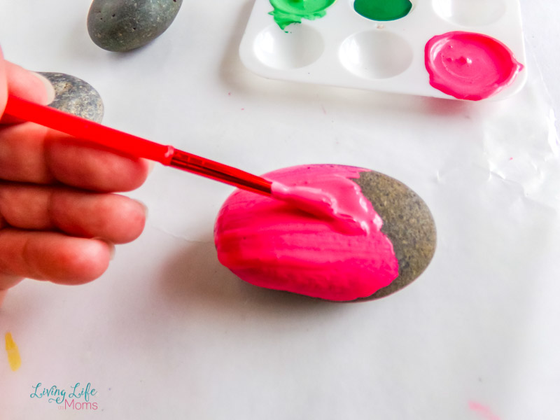 Painting a rock with pink paint with a paintbrush