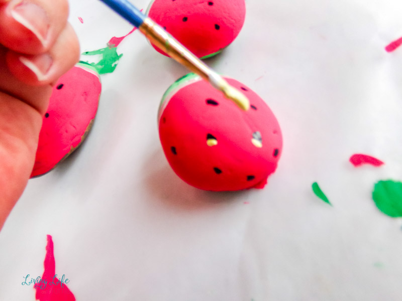 Adding white paint to the black seeds for the watermelon painted rocks