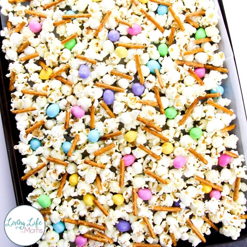 adding pretzel sticks and M&M to popcorn 