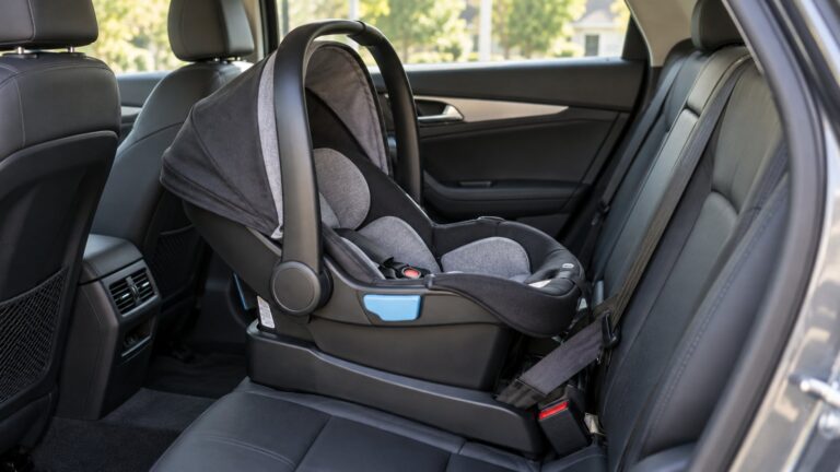 A rear-facing infant car seat securely installed in the back seat of a car, interior daylight, no child - Car Seat Stages: When to Switch From Rear-Facing, Forward-Facing and Booster